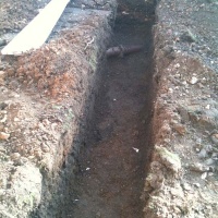 Foundation trench excavated with care and clay storm drain left intack